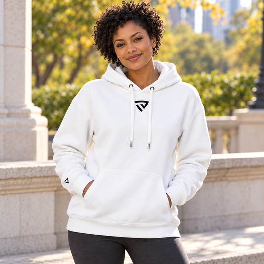 Women's Legacy Hoodie worn by an adult woman in a bright city park terrace beside pale stone and soft autumn greenery; front view.
