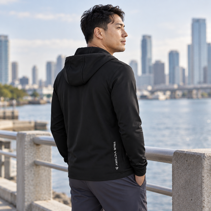 Rear three-quarter view of the black Elite Full-Zip showing its lower-side True Victory detail by the waterfront.