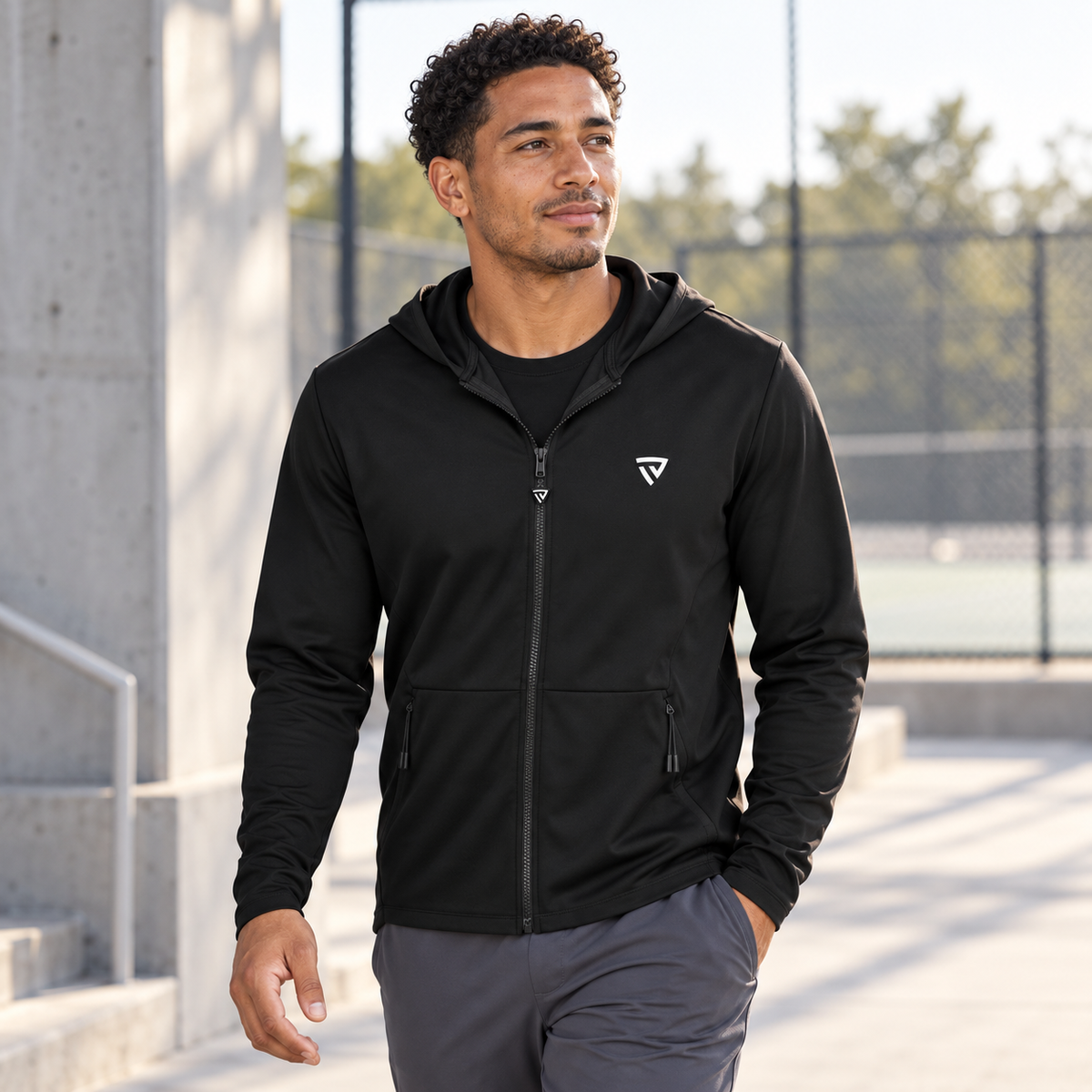 Man wearing the black True Victory Elite Full-Zip beside an outdoor training court.
