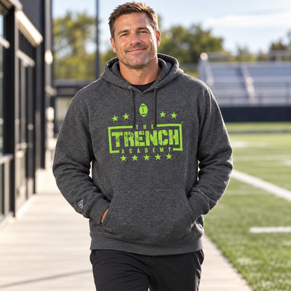 Man wearing the Trench Hold the Line Charcoal Hoodie outside a training facility.