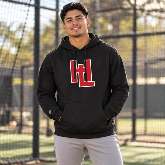 Man wearing the black HitLab Hoodie outside a batting cage.