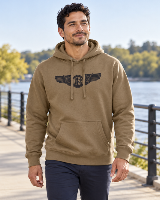 Man wearing the coyote brown AFSA Wings Hoodie with black chest graphic beside a river.